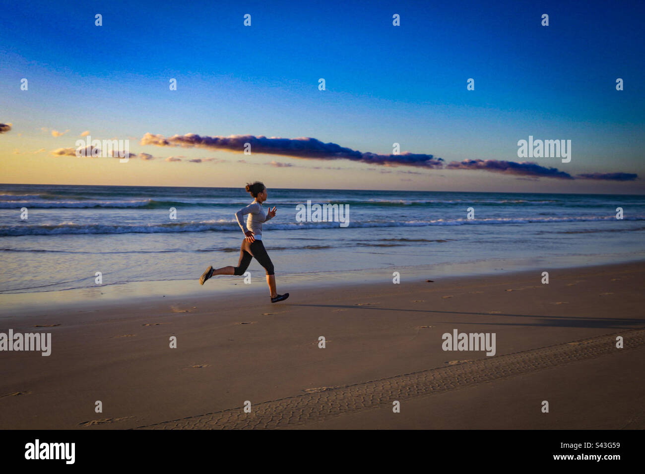Sprint training lungo la spiaggia orientale di K’gari (Isola Fraser). Donna asiatica che corre sulla sabbia all'alba. - Immagine stock catturata con smartphone