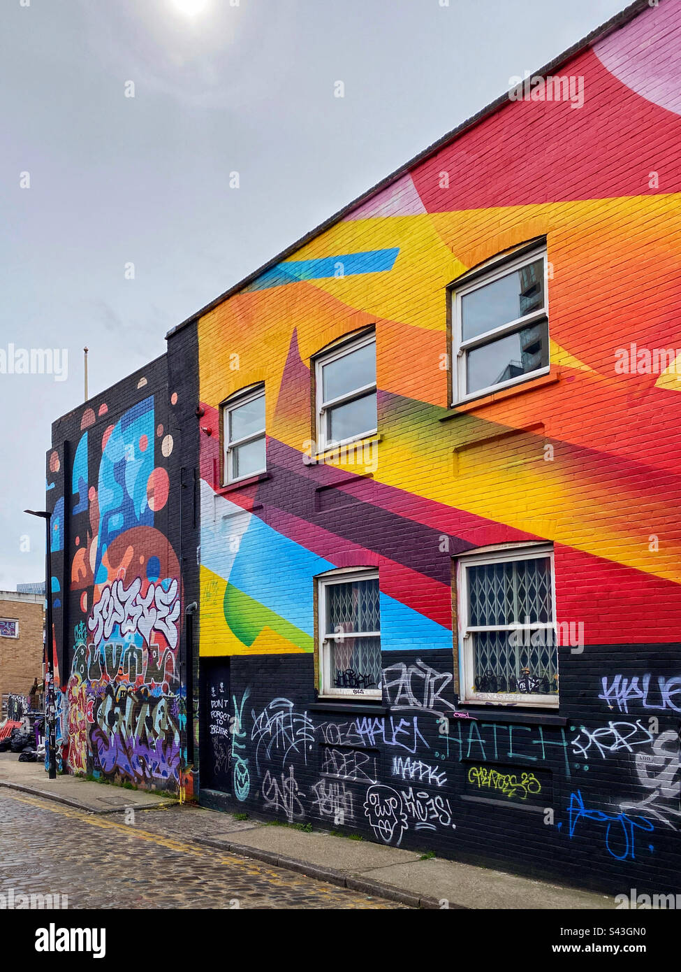 Un edificio molto colorato! I graffiti e i colori luminosi adornano il lato di un edificio. È creativo? È un pasticcio? È arte? È antisociale? Decidi tu! Foto ©️ COLIN HOSKINS. - Immagine stock catturata con smartphone