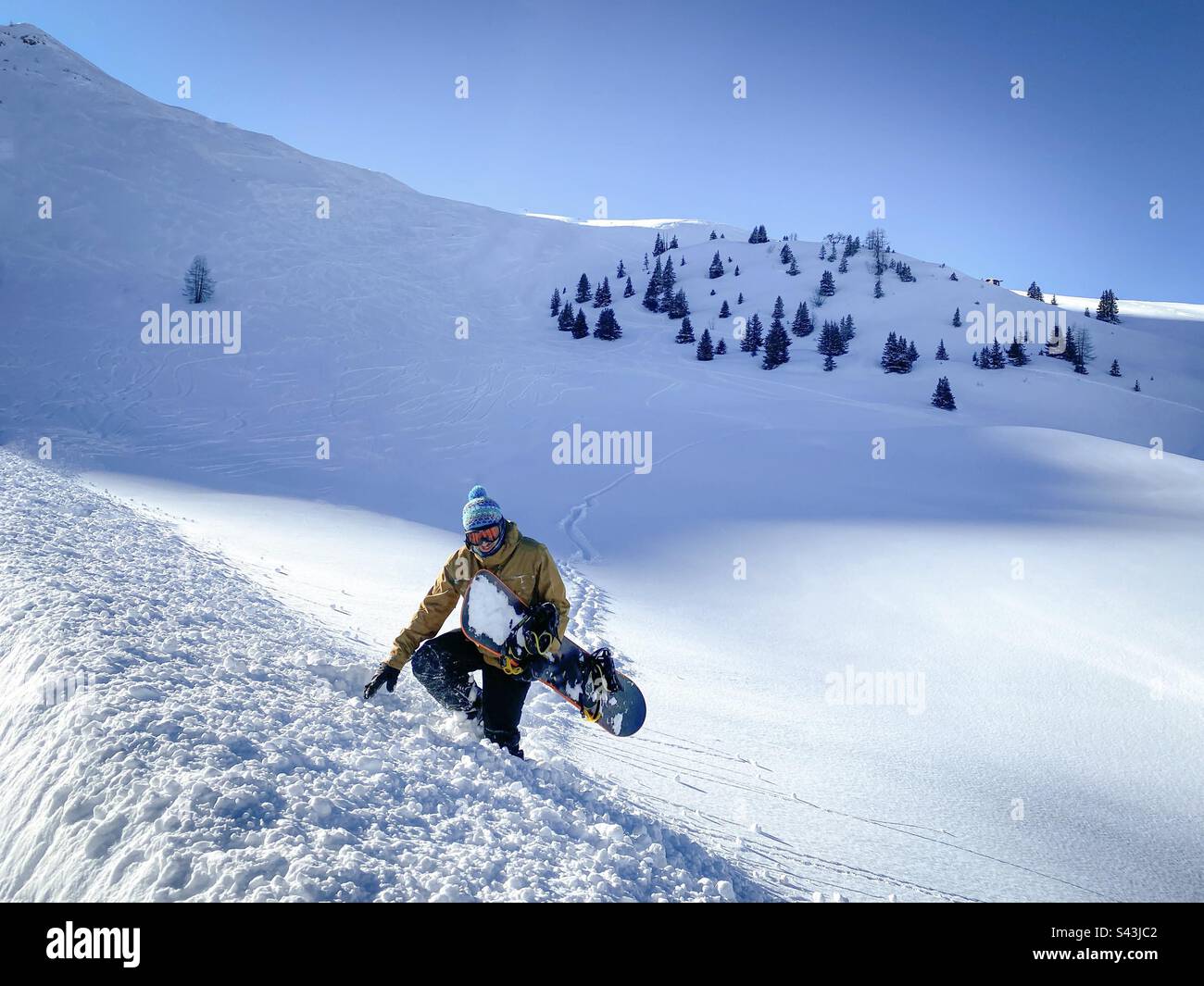 Snowboarder escursioni fuori dalla polvere profonda dopo essere rimasto bloccato su una pista da sci incontaminata. - Immagine stock catturata con smartphone