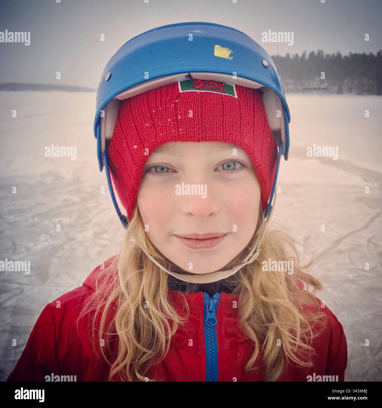 Un ritratto di una giovane ragazza di 10 anni in un casco di pattinaggio su ghiaccio su un lago in inverno profondo in Scandinavia Foto Stock
