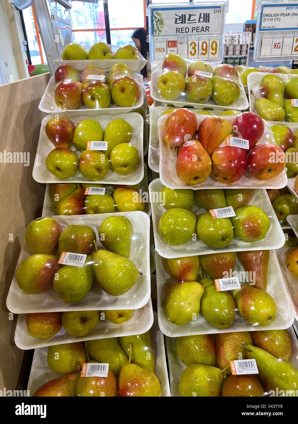 Pere confezionate in vaschette di polistirolo e film plastico, impilate e in vendita in un supermercato. Foto Stock