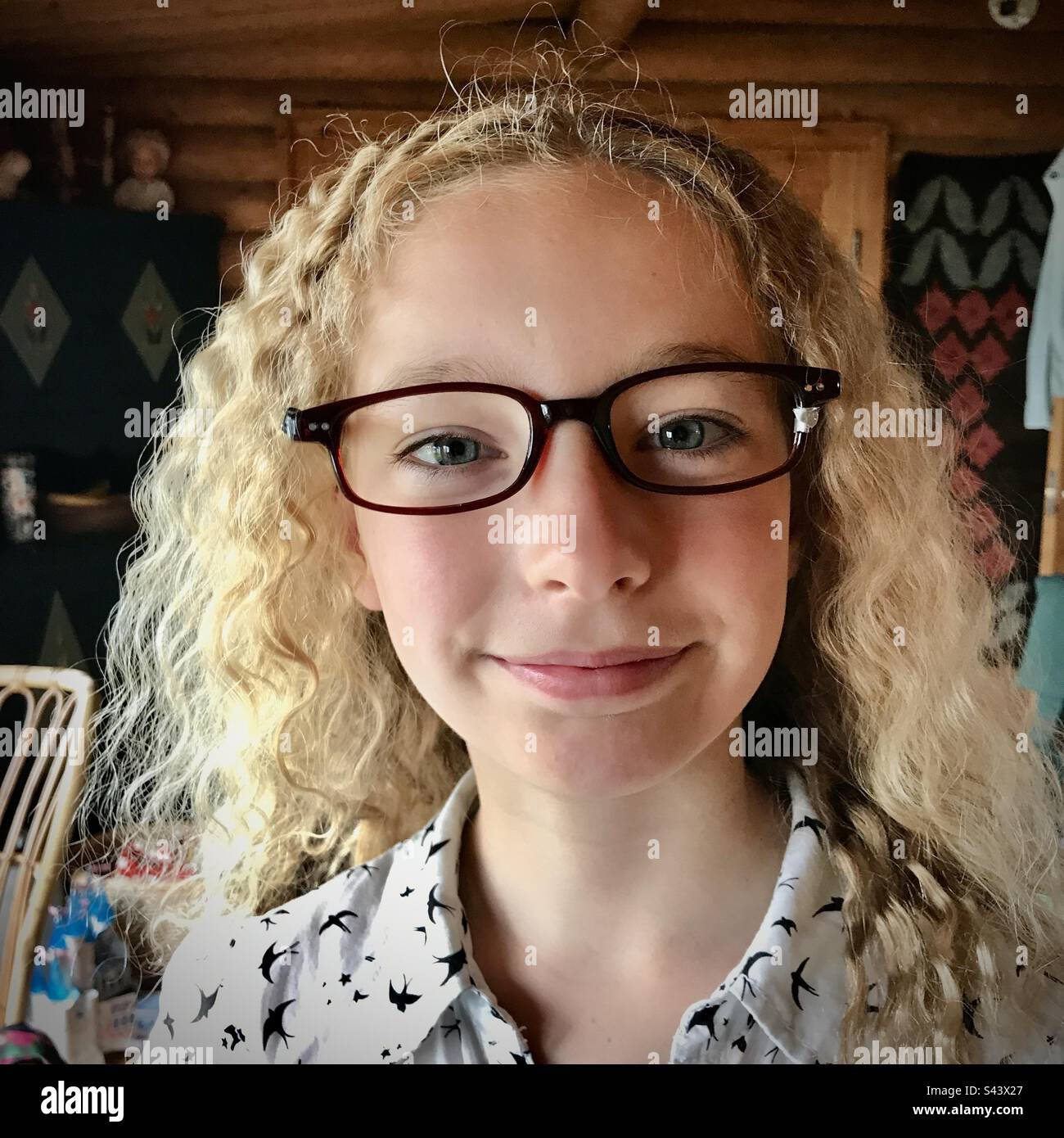 Una ragazza giovane figlia di 9 anni sorridente in vacanza con capelli molto ricci e crespi indossare occhiali riparati con un nastro fare Foto Stock