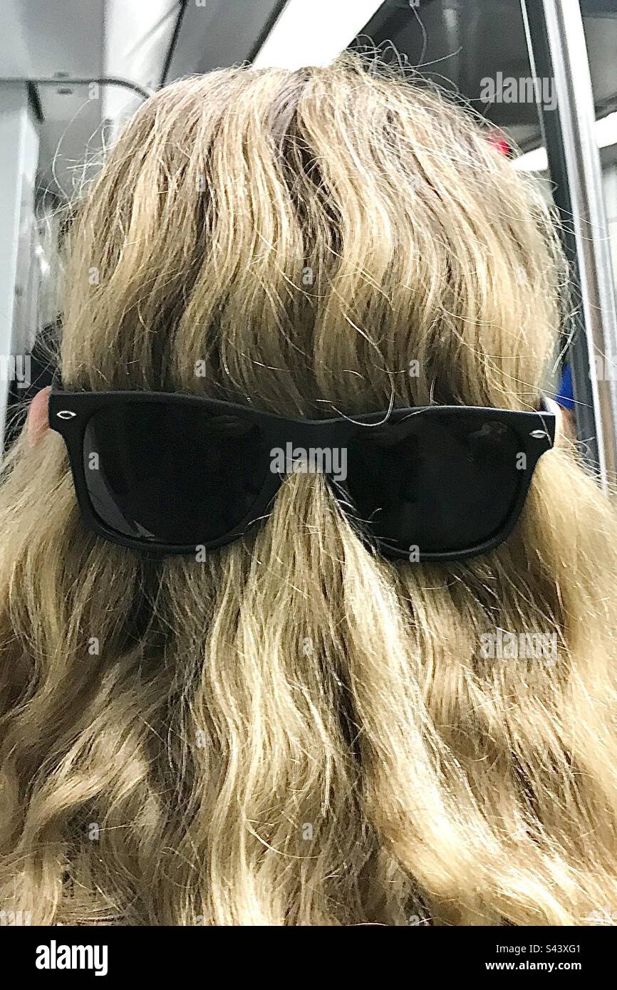 Una bambina di 9 anni, figlia di una bambina, che si scompigliava di avere un pungente che indossava gli occhiali a ritroso su un treno sotterraneo della metropolitana Foto Stock