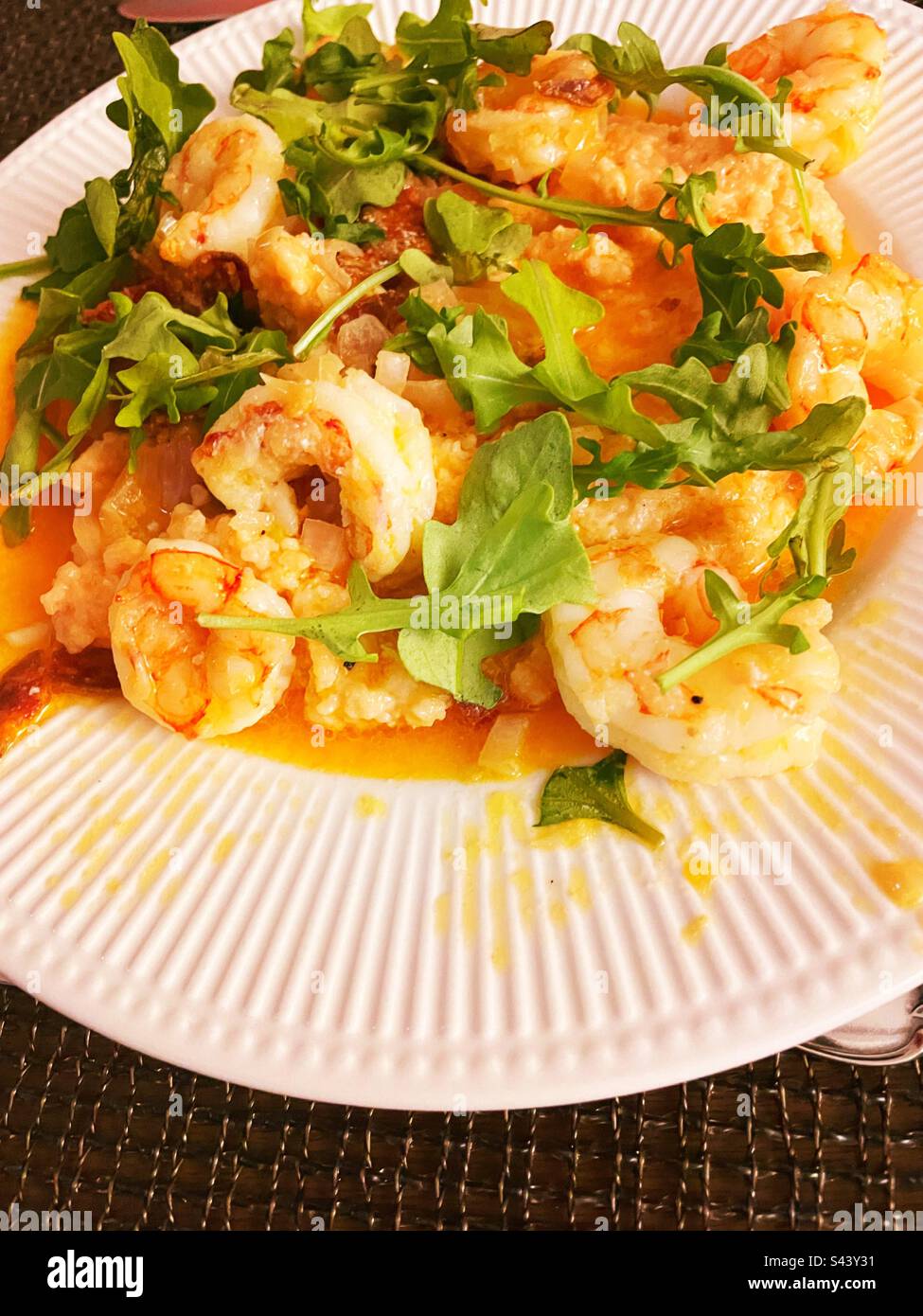 Primo piano di un entrée, gamberi e fiocchi di mare preferiti dal sud della bassa campagna con contorno di rucola, 2023, USA - Immagine stock catturata con smartphone