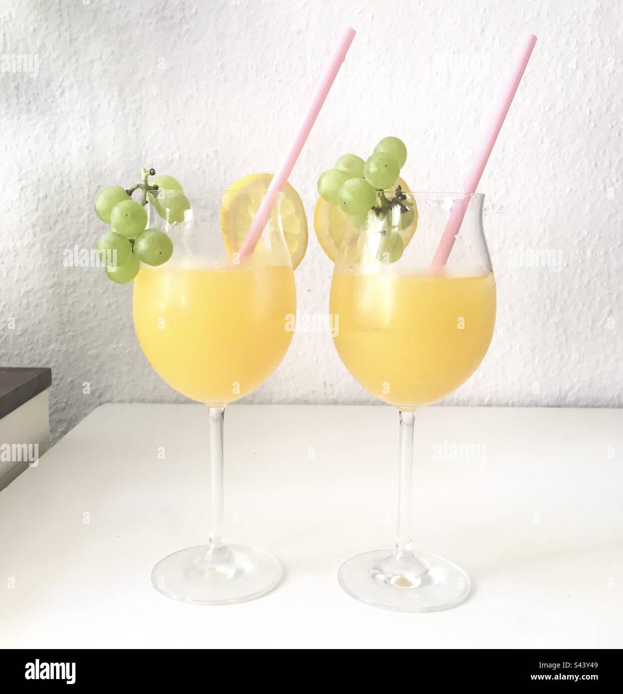 Cocktail drink fruttati e luminosi guarniti con uva e una fetta d'arancia - Immagine stock catturata con smartphone