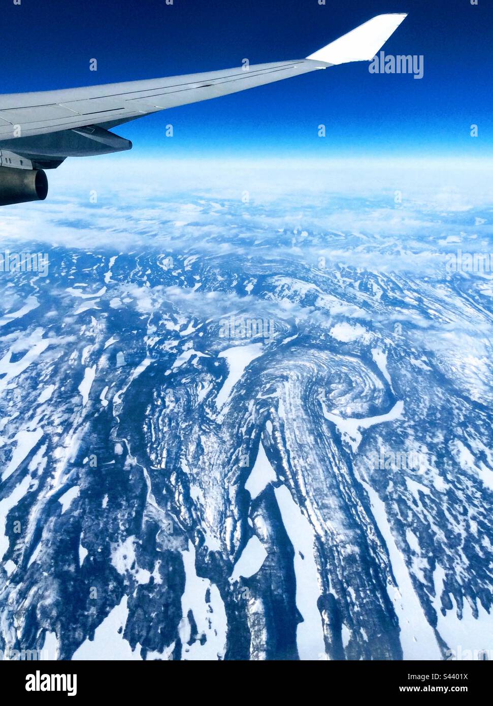 In alto nell'aria: Vista mozzafiato sulle montagne innevate dalla finestra dell'aeroplano - Immagine stock catturata con smartphone