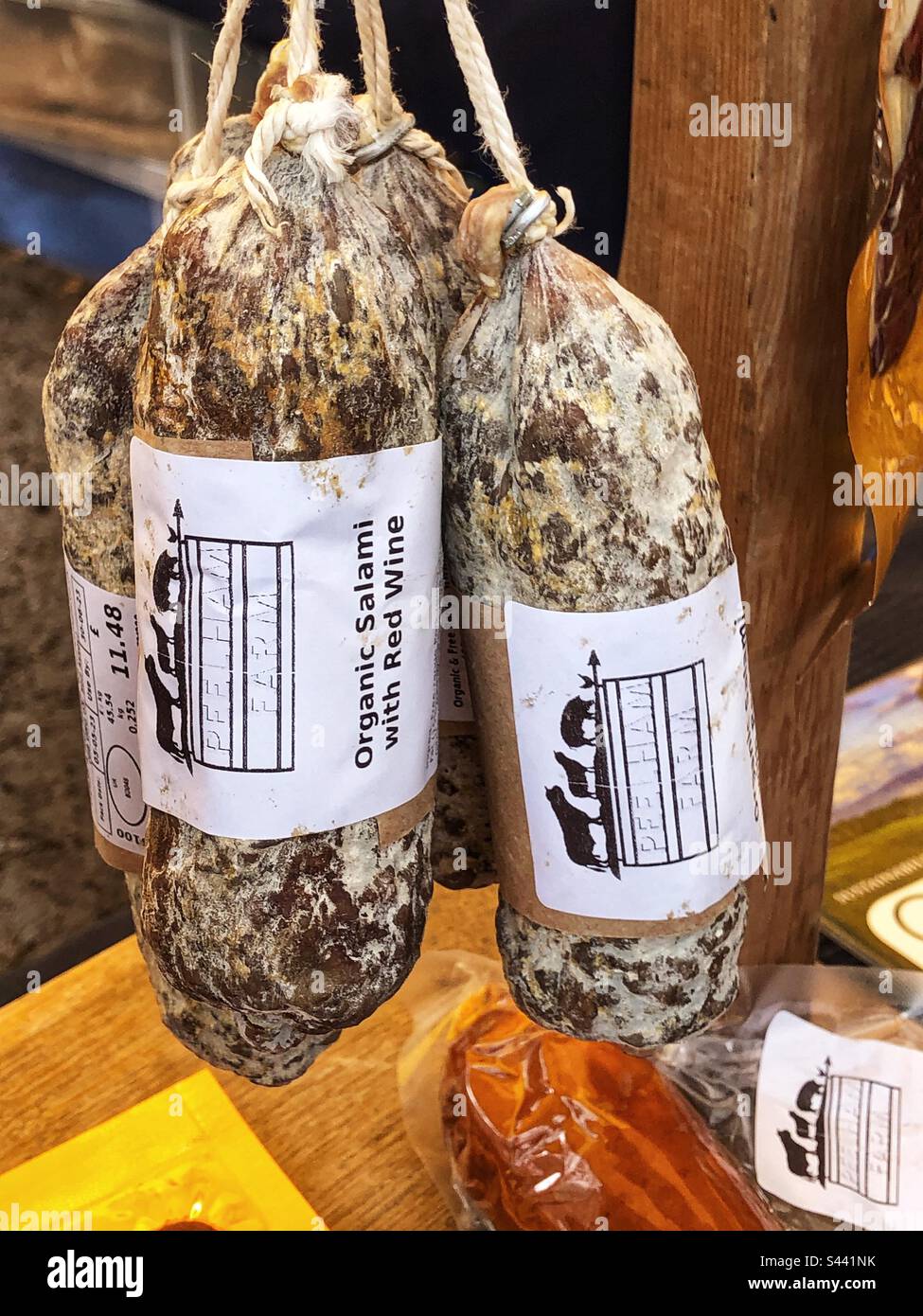 Salame biologico di specialità con tagli di carne al vino rosso in vendita presso lo stand del mercato agricolo locale Foto Stock