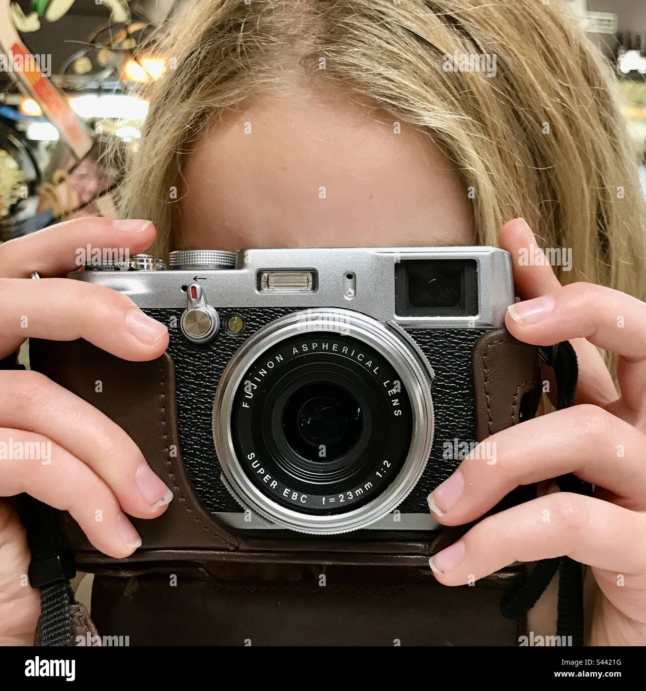 Giovane ragazza di 10 anni che impara nuove abilità scattando una foto con una vecchia macchina fotografica di stile un modello originale fujifilm x100 Foto Stock