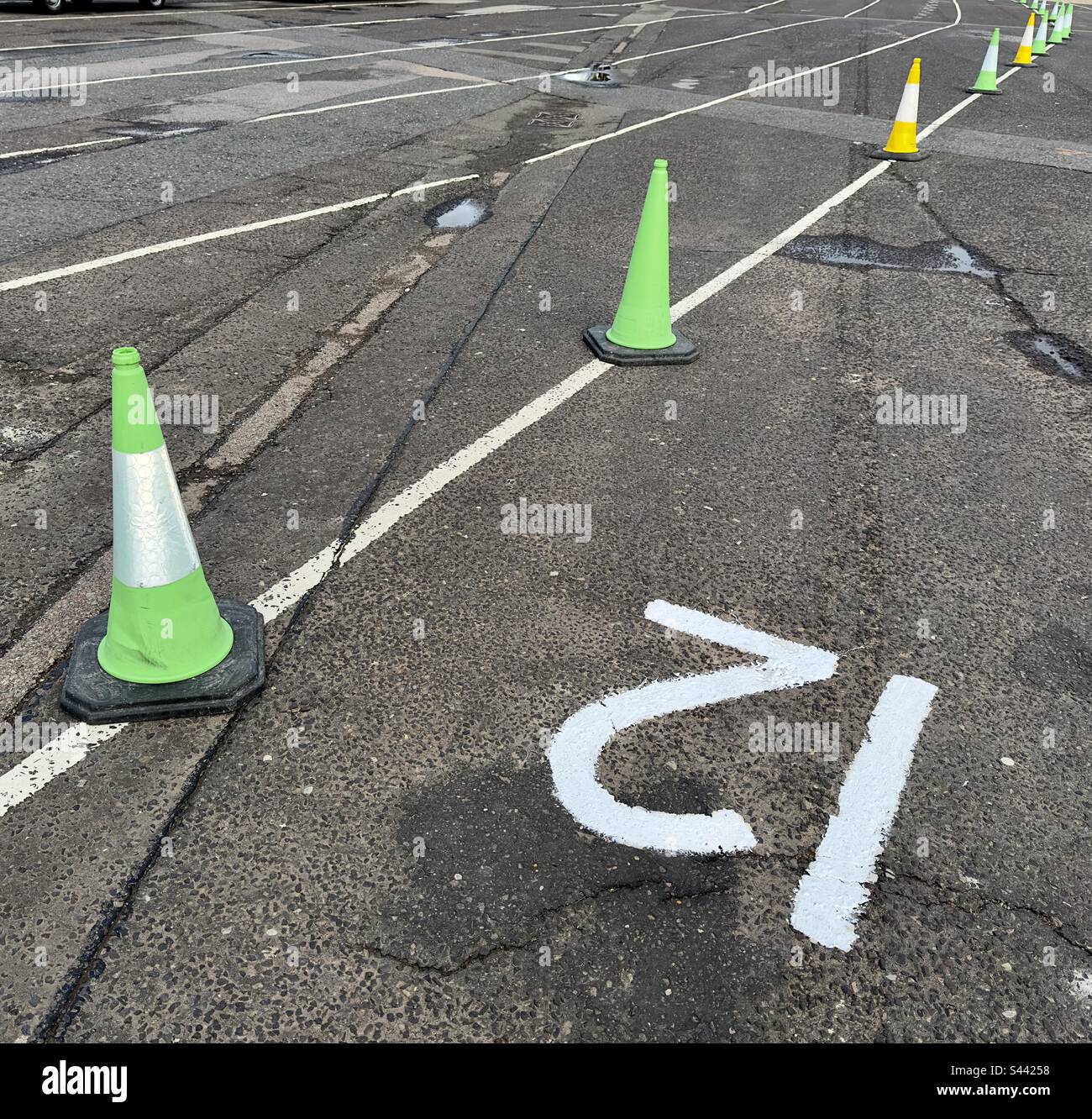 Il parcheggio vuoto di un terminal dei traghetti le linee segnate da coni stradali verdi e gialli e il numero 12 in primo piano - Immagine stock catturata con smartphone