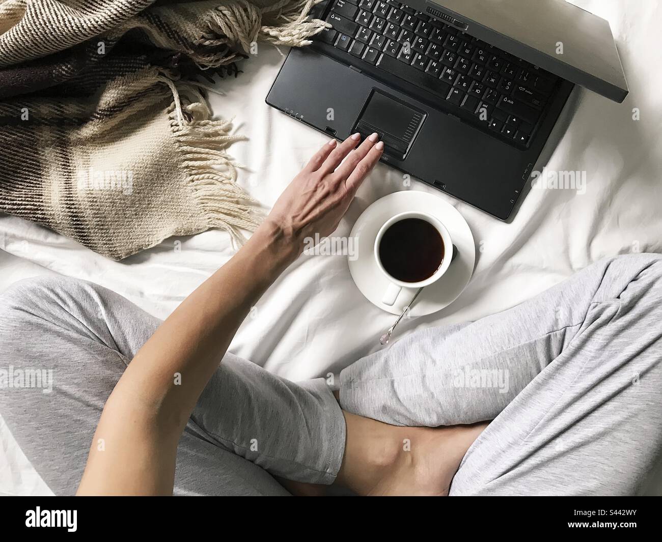 Computer portatile e tazza di caffè a letto durante i weekend più pigri Foto Stock