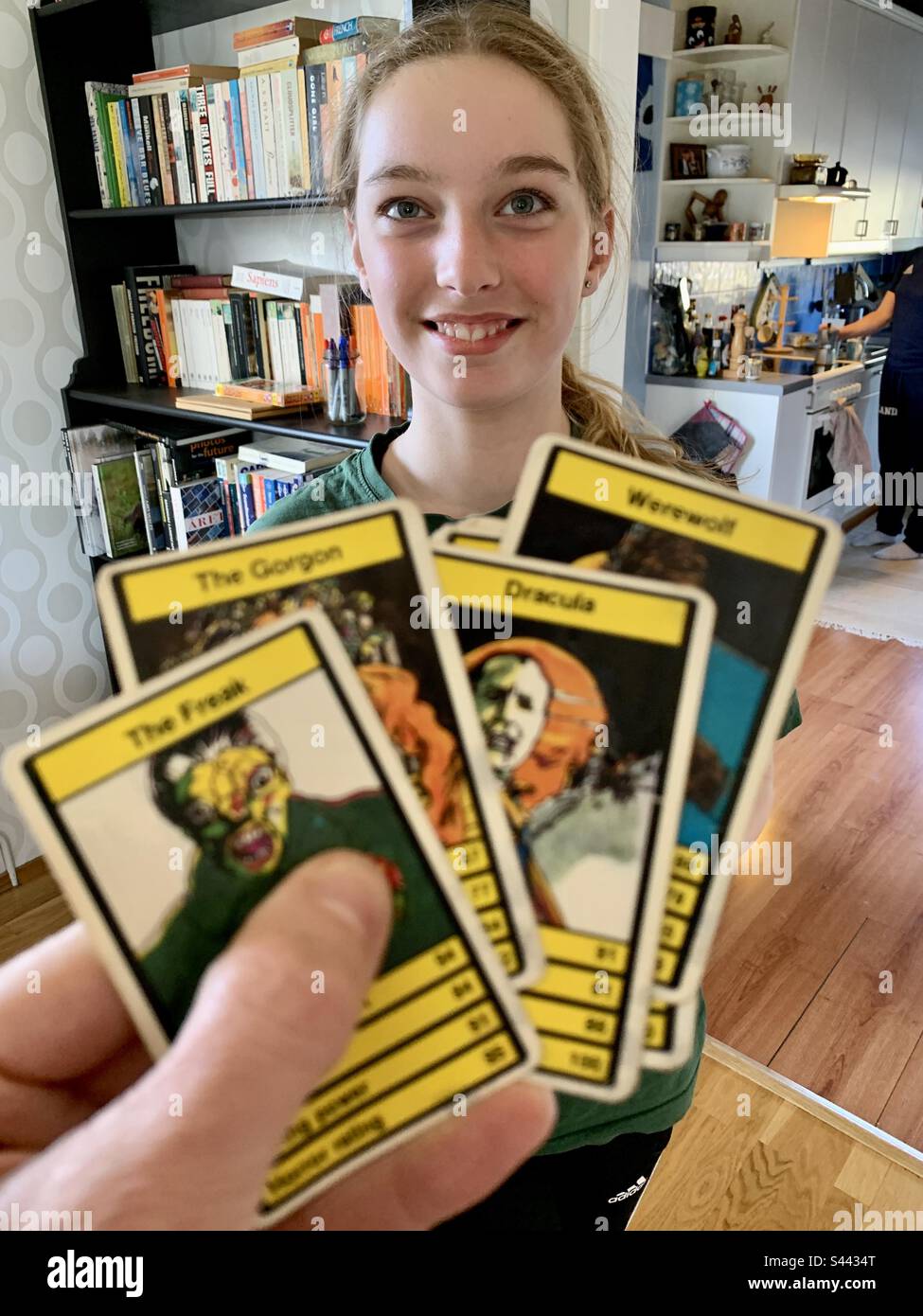 Una giovane ragazza di 9 anni che gioca il gioco di carte 1970s Top Trumps (famosa versione carte Horror) su Halloween a casa divertirsi Foto Stock