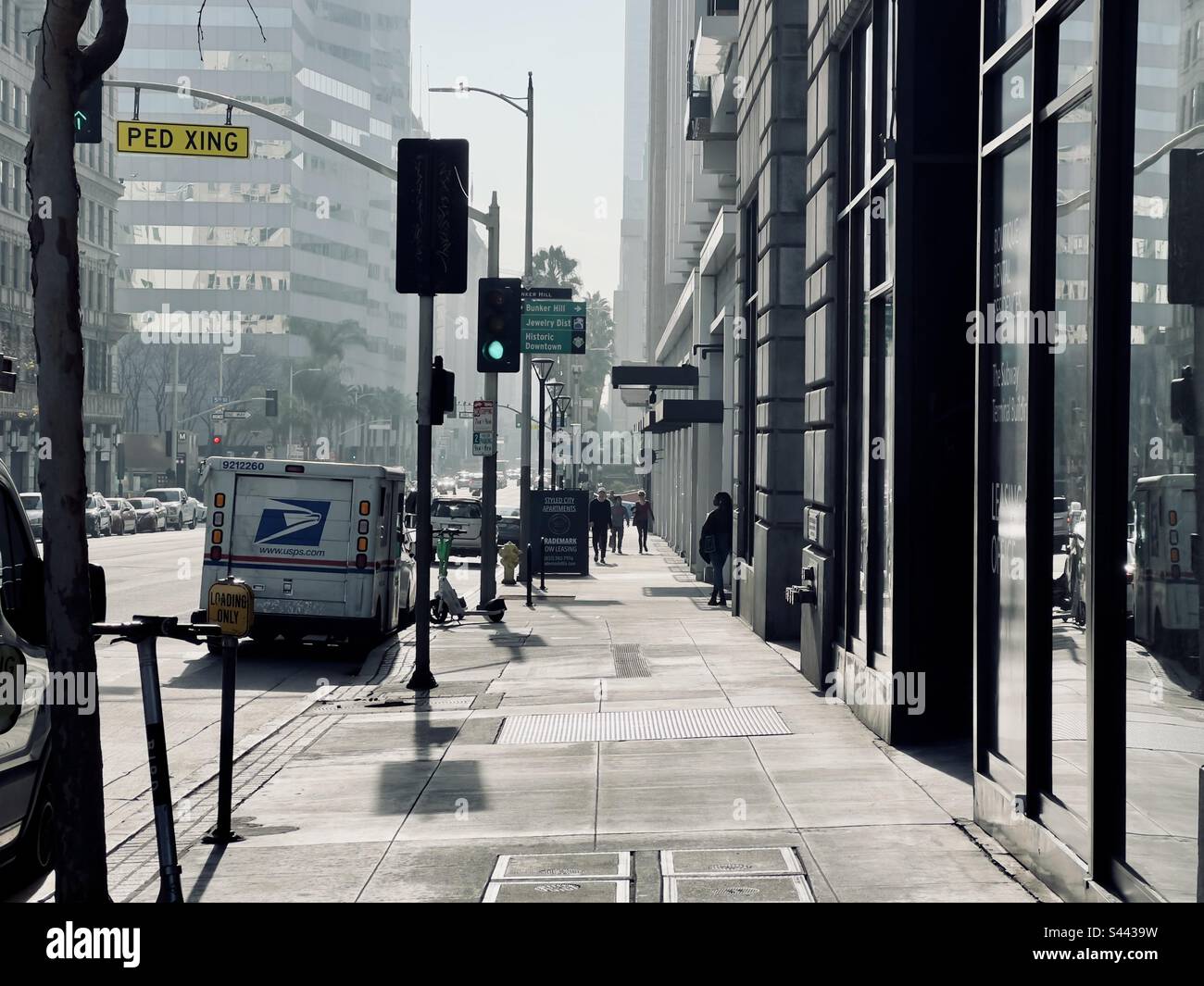LOS ANGELES, CA, DEC 2022: Guardando verso sud su Hill Street nel centro, verso i pedoni sul marciapiede e il furgone USPS parcheggiato sul lato della strada, il sole invernale basso crea un contrasto elevato - Immagine stock catturata con smartphone