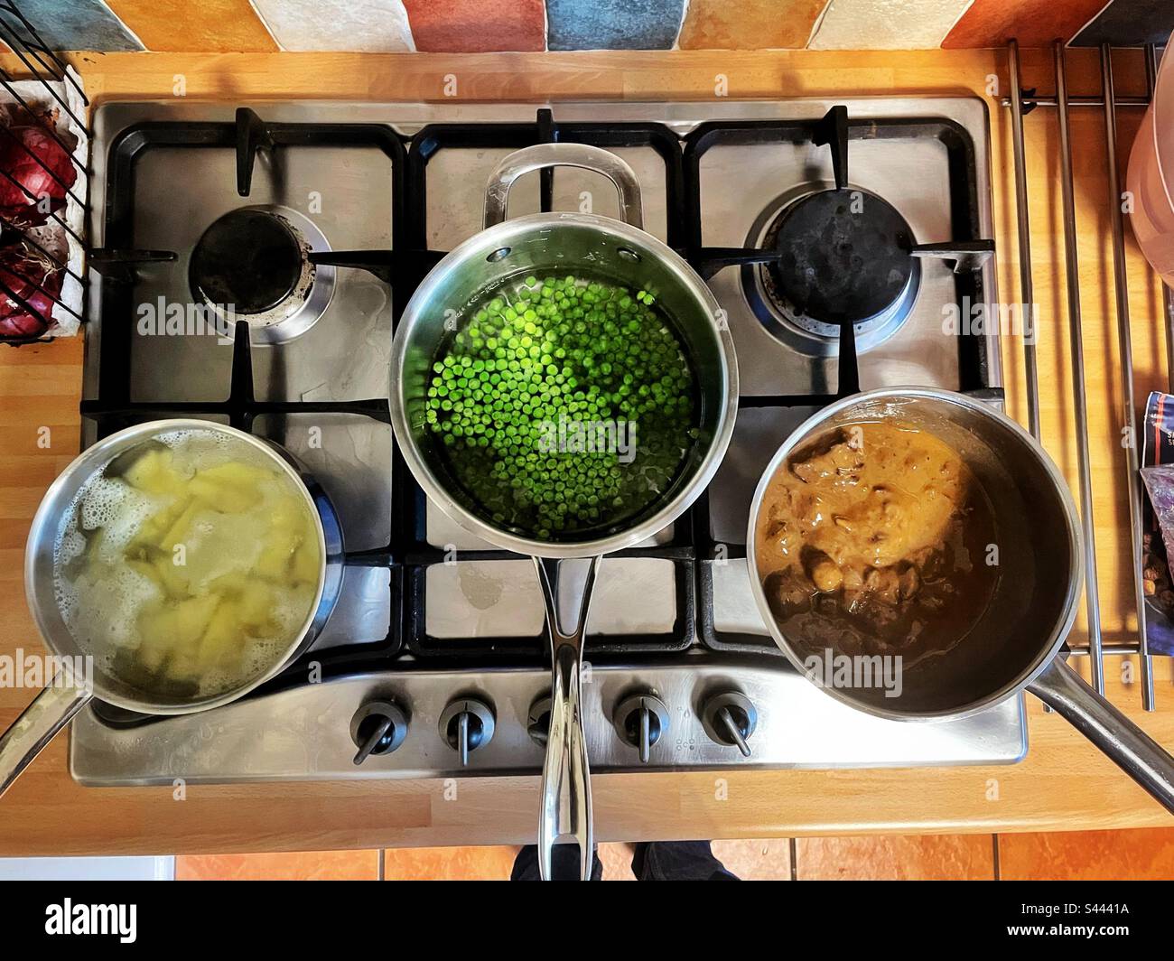 Tre pentole che cucinano il cibo su un piano cottura a gas. Foto Stock