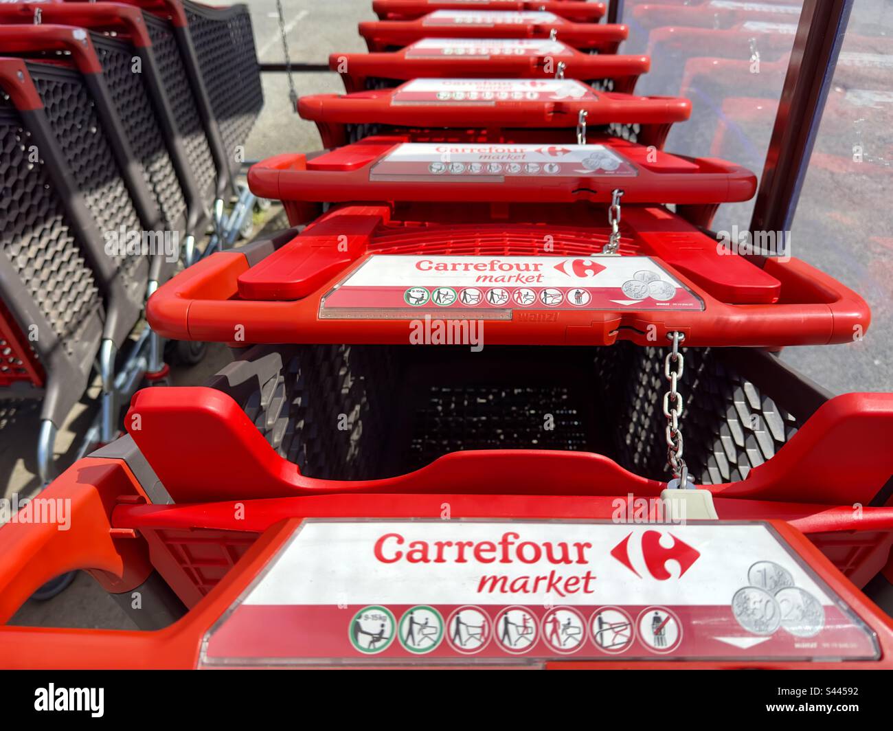 Le maniglie rosse dei carrelli di shopping fuori di un supermercato francese. Foto Stock