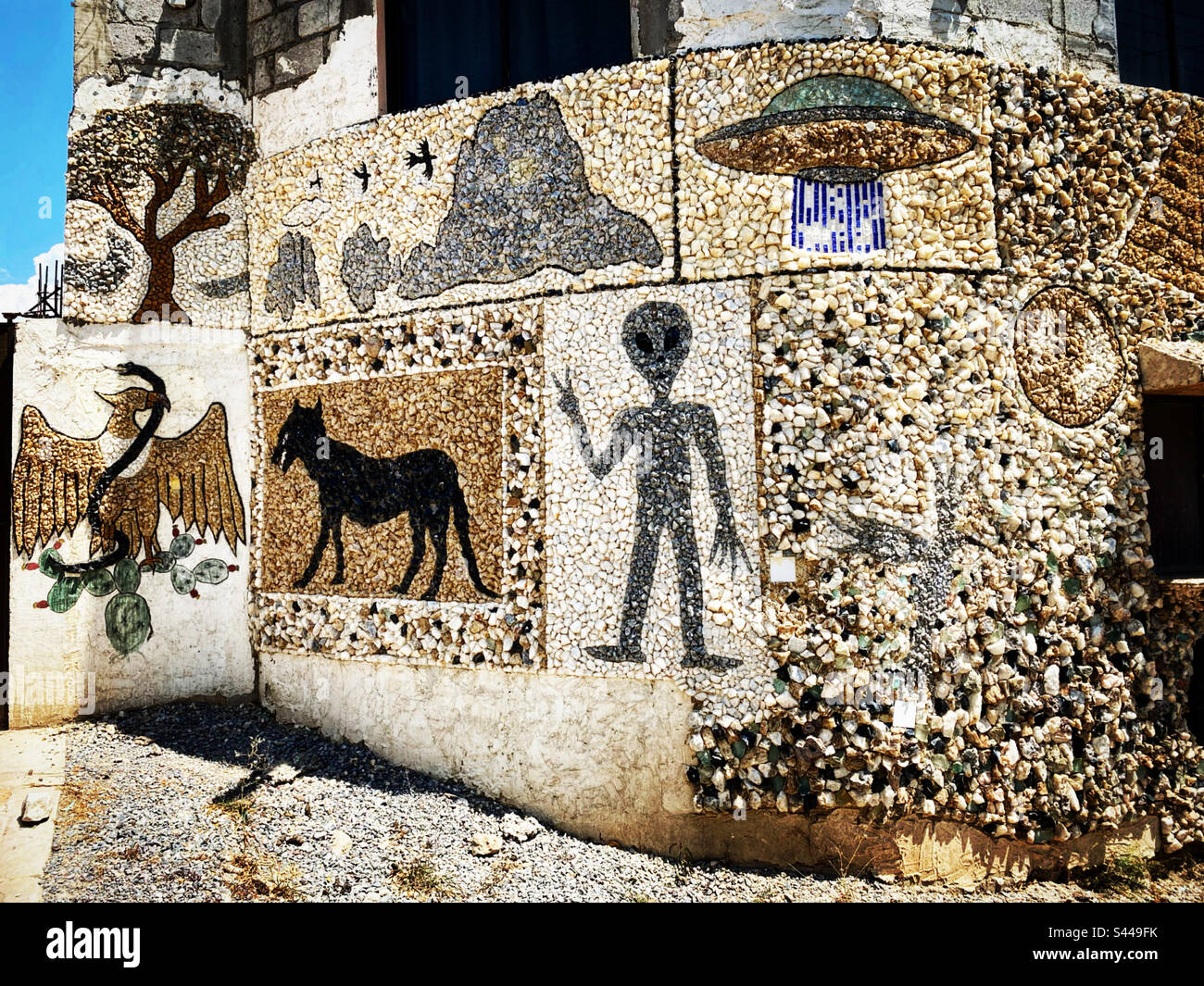 Un muro decorato con un alieno, un cane nero, un UFO, il simbolo messicano di un'aquila che mangia un serpente e una riproduzione della montagna monolitica Peña de Bernal decorano una casa in Messico Foto Stock
