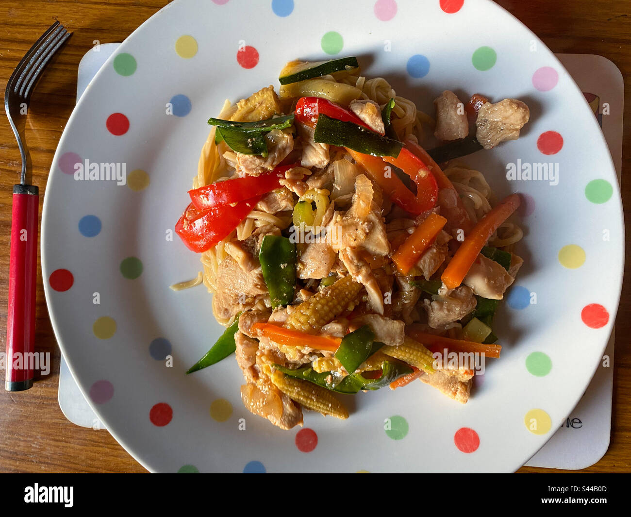 Piatto cucinato in casa di pollo fritto e verdure miste con spaghetti di uova su un piatto visto dall'alto. Foto Stock
