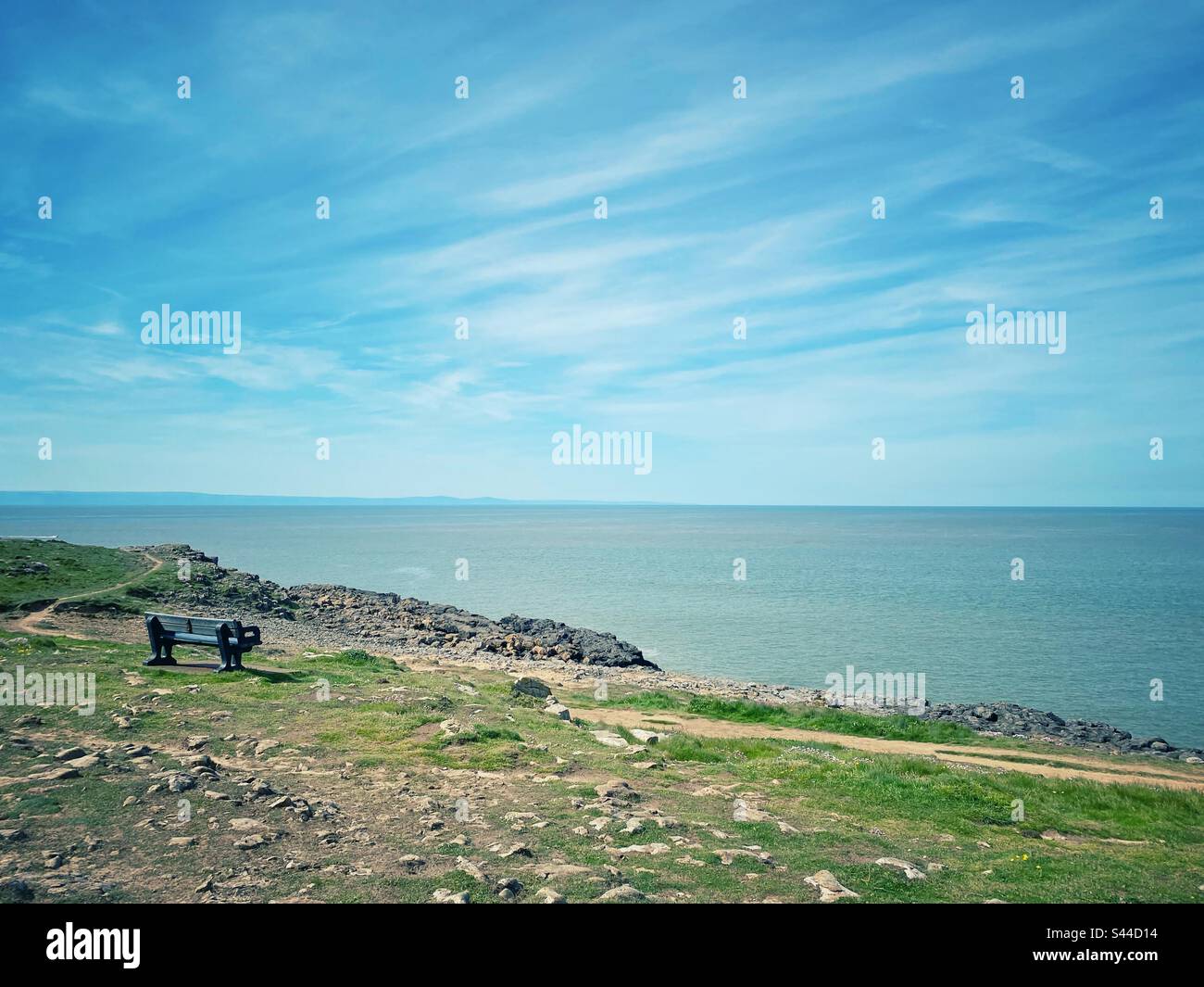 Una fotografia di una panchina su una scogliera costiera che si affaccia sull'oceano Foto Stock