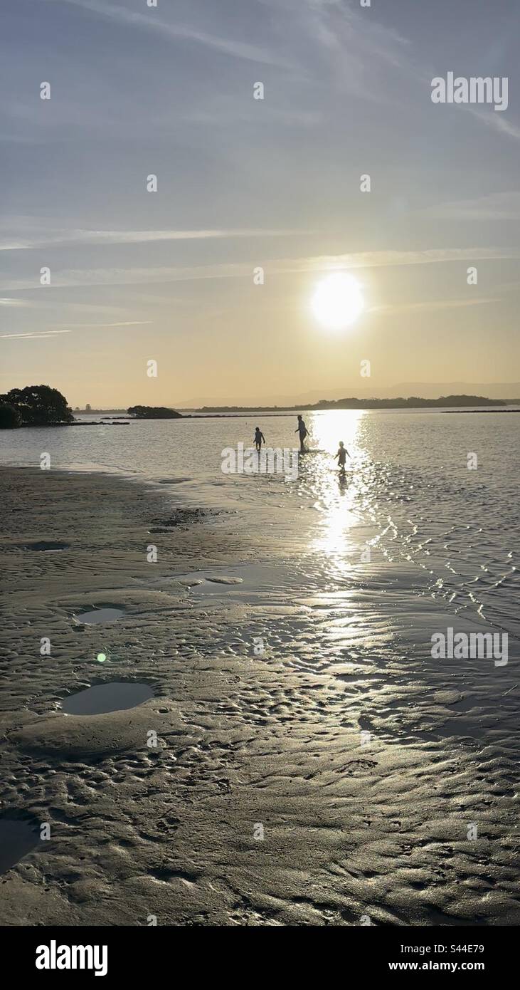 Bambini che giocano sulla spiaggia al tramonto Foto Stock