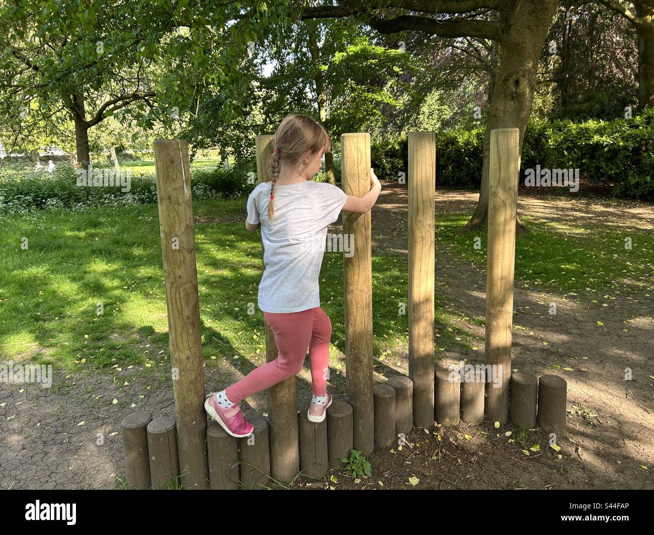Ragazza che si avvolge attraverso attrezzature da gioco in legno Foto Stock