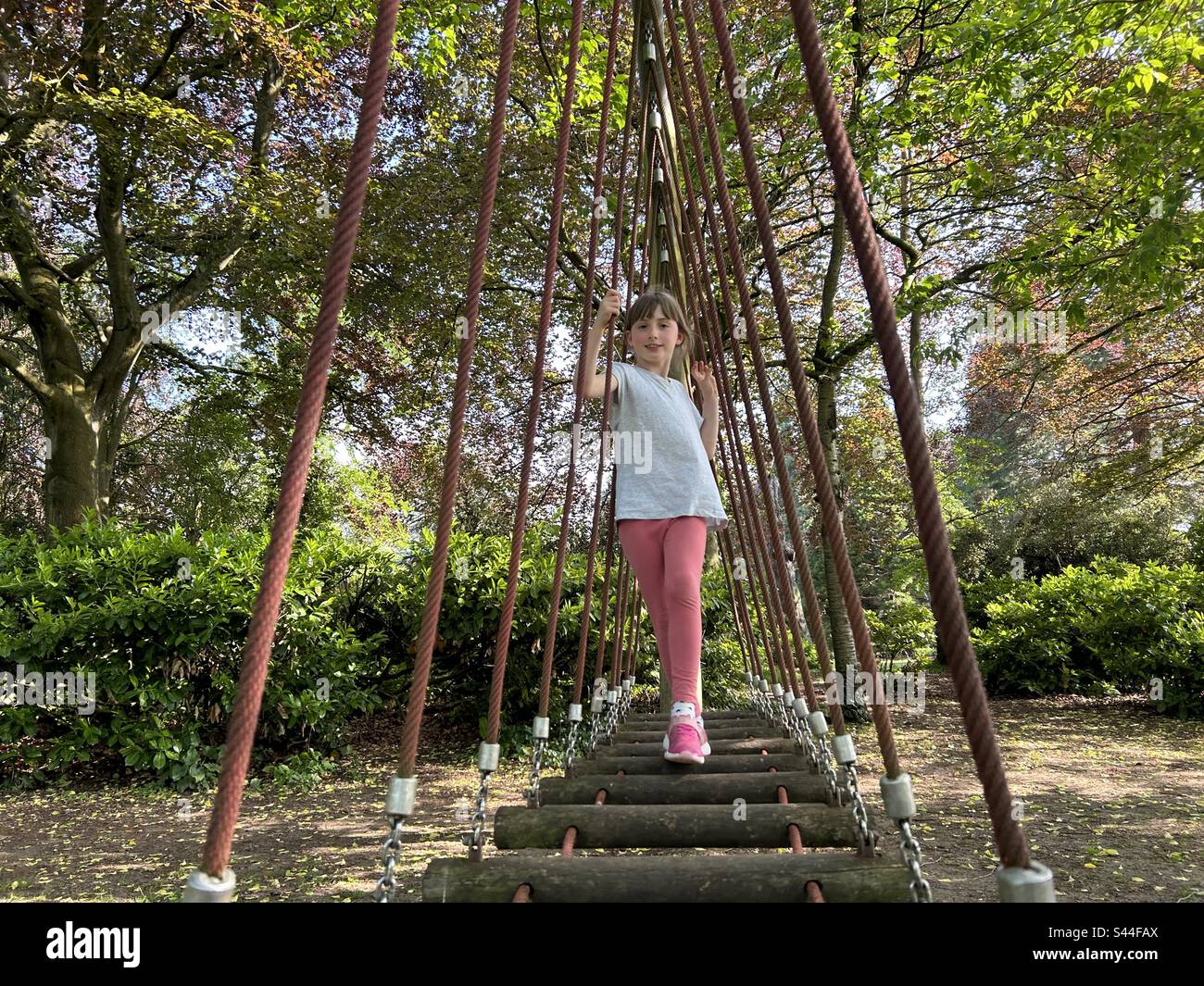 Ragazza sul parco giochi. Ponte sospeso in corda - Immagine stock catturata con smartphone