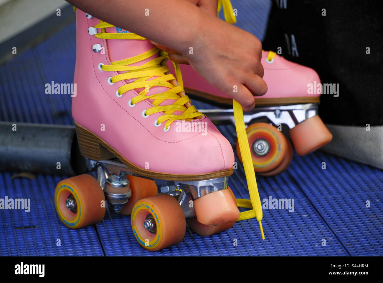 Posizionamento dei pattini rosa sulla pista del rullo Foto Stock