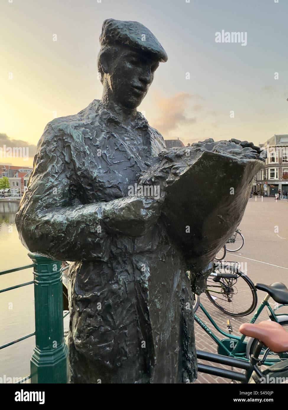 Una piccola statua in bronzo raffigurante un venditore di fiori, una di una serie raffigurante il commercio di Leiden nei Paesi Bassi. Foto Stock