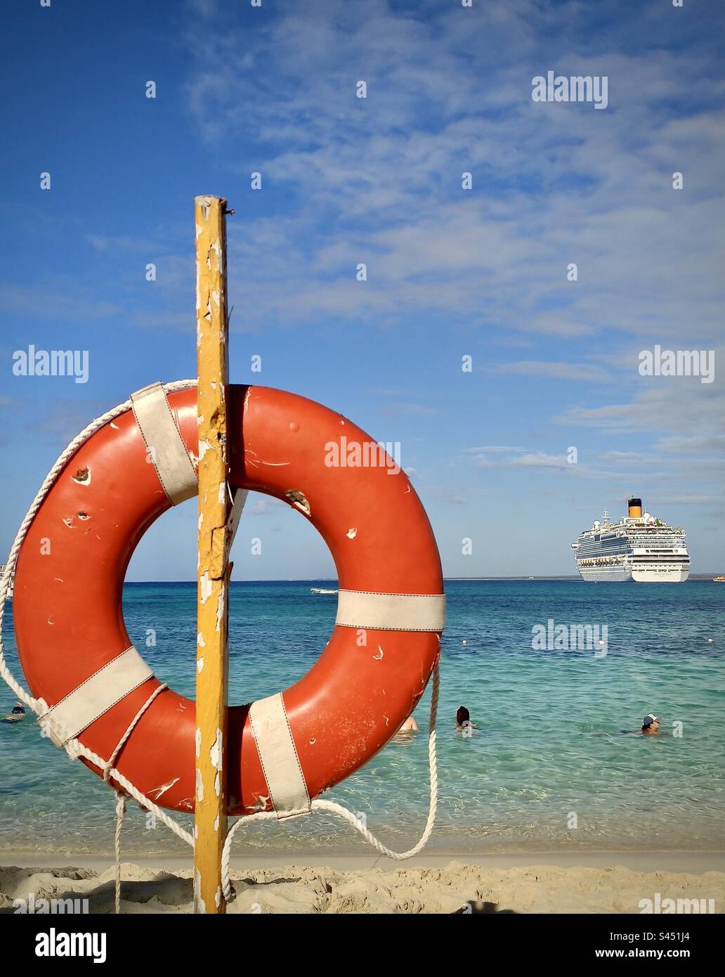 Vista di una spiaggia caraibica con un'ancora di salvezza rossa in primo piano e una nave da crociera sullo sfondo. Foto scattata nella Repubblica Dominicana nel dicembre 2019 Foto Stock