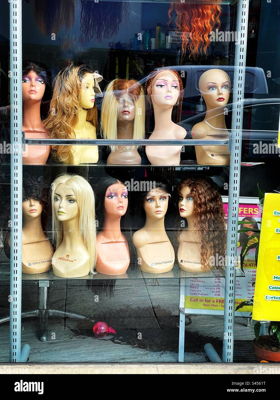 Modella le teste in una vetrina che mostra parrucche in vendita. - Immagine stock catturata con smartphone