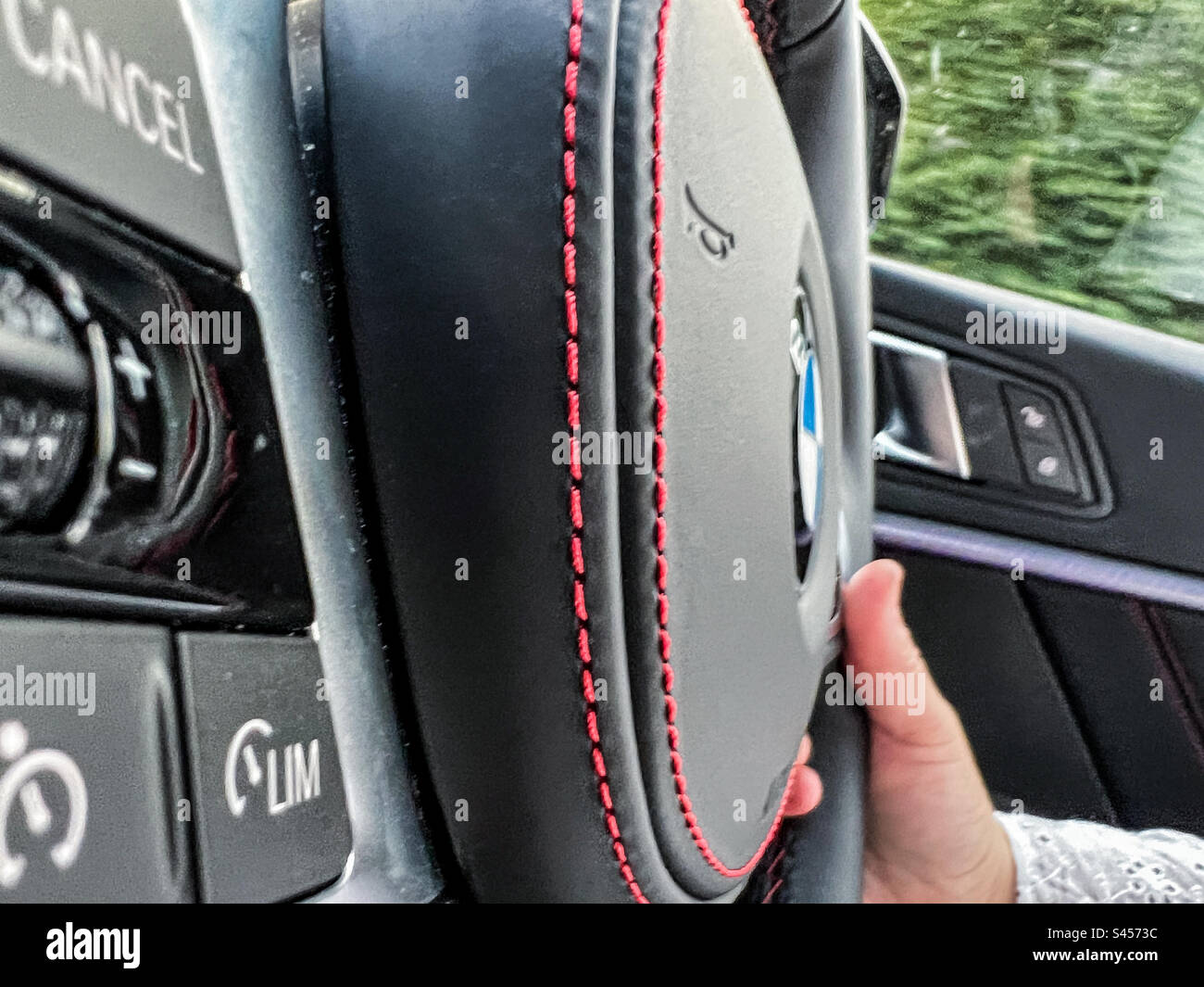 Guida di un'auto BMW con un primo piano del volante M Sport - Immagine stock catturata con smartphone