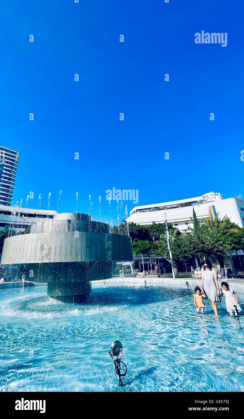 La madre e le sue figlie camminano nella fontana di piazza Dizengoff a Tel-Aviv, Israele. - Immagine stock catturata con smartphone