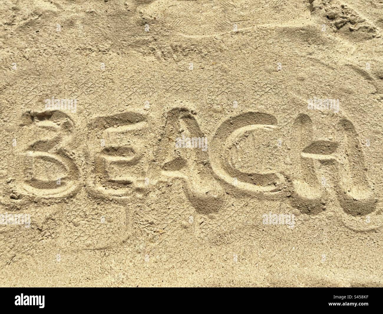 La parola “Spiaggia” scritta in sabbia fine su una spiaggia tropicale. Foto Stock