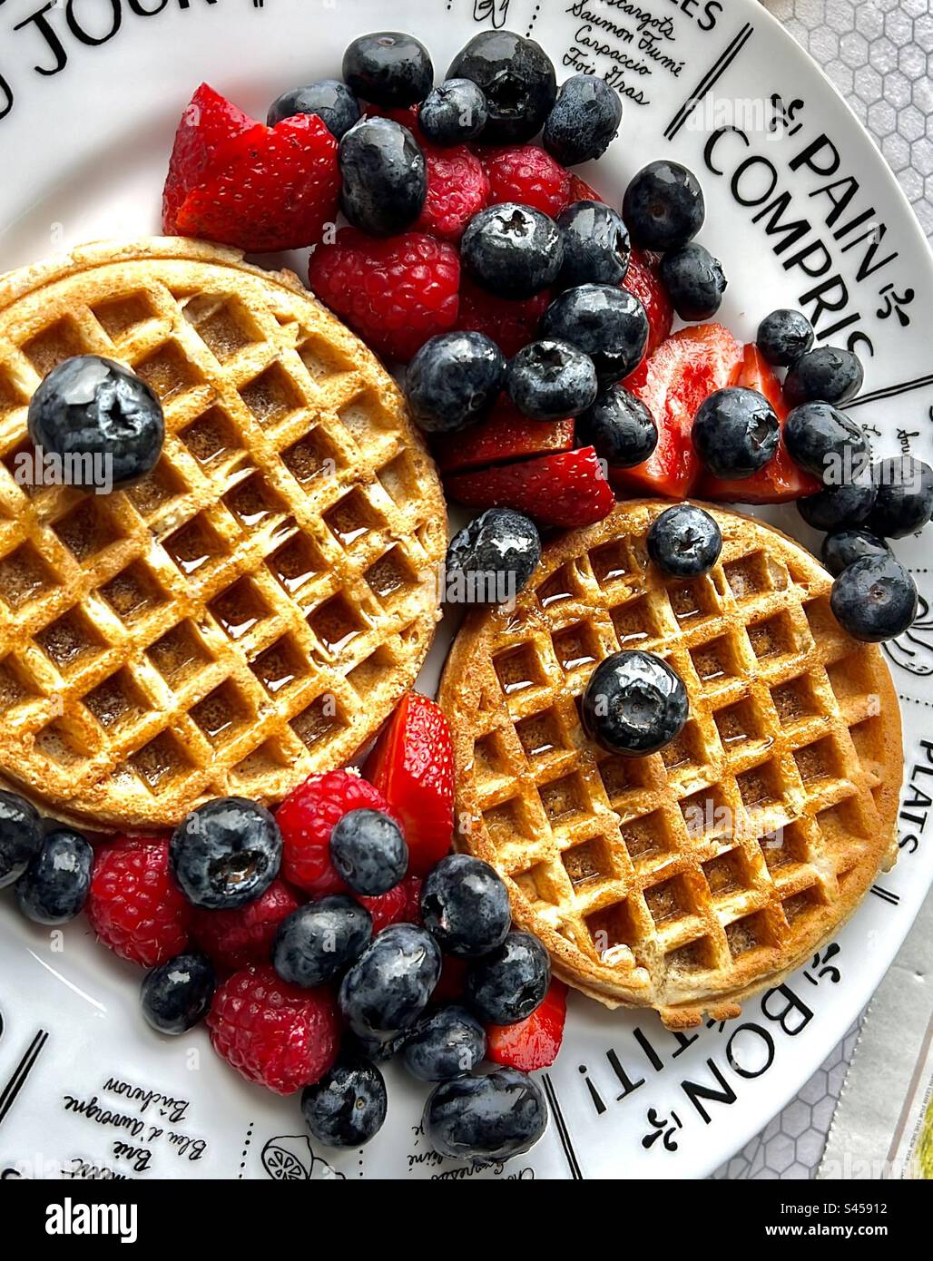 Waffle e frutta fresca estiva di mirtilli, lamponi, fragole con sciroppo d'acero canadese per una colazione gréât. Foto Stock