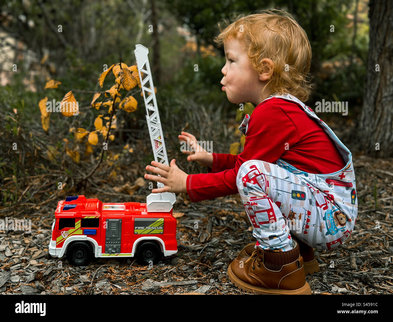 Bambino che gioca all'aperto con un camion dei pompieri Foto Stock