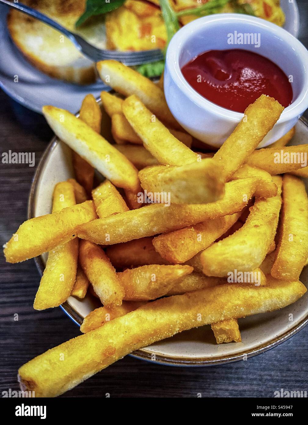 Primo piano di patatine fritte con ketchup in una piccola ciotola sul tavolo. Cibo di conforto. Mangiare malsano. Contorno. Foto Stock