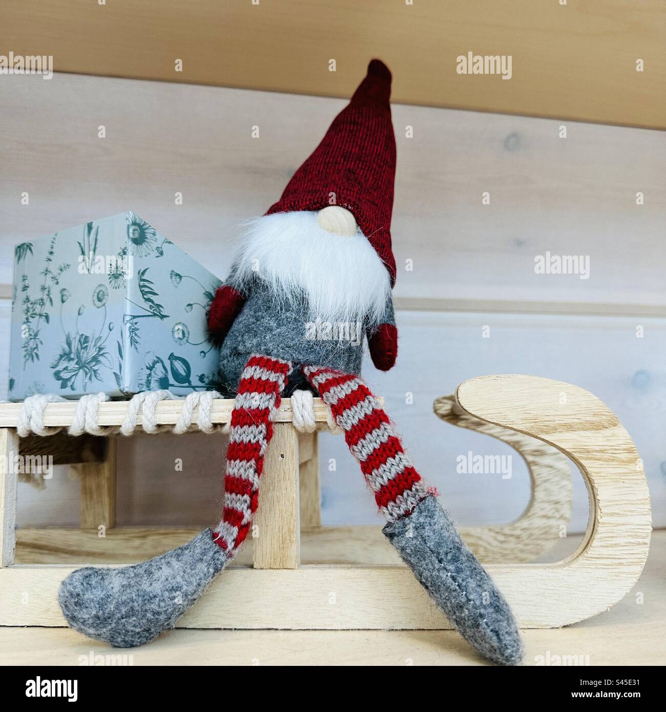 Babbo Natale, giocattolo felpato nella cabina natalizia dell'aeroporto di Helsinki, seduto su una slitta di legno con un regalo confezionato Foto Stock