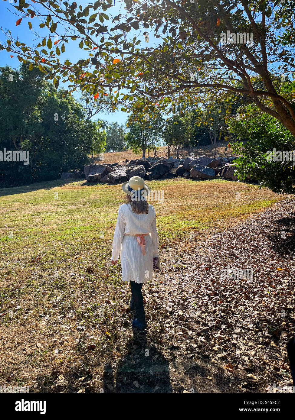 Giovane ragazza con vestito bianco e cappello di paglia che se ne va Foto Stock