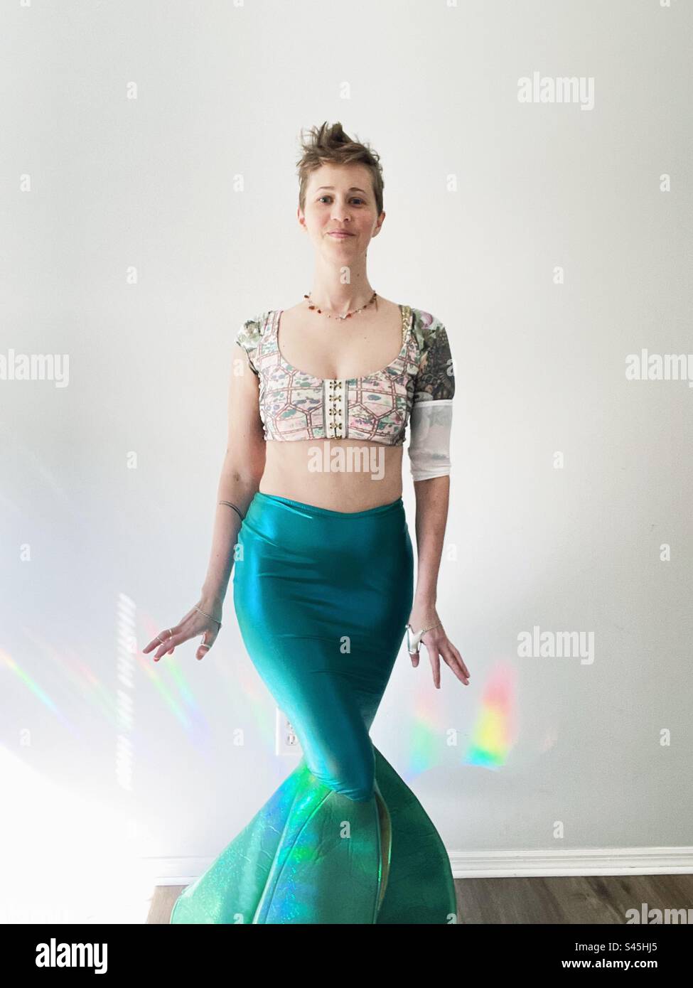 Donna vestita con coda a sirena con copertura picc line e luce arcobaleno Foto Stock