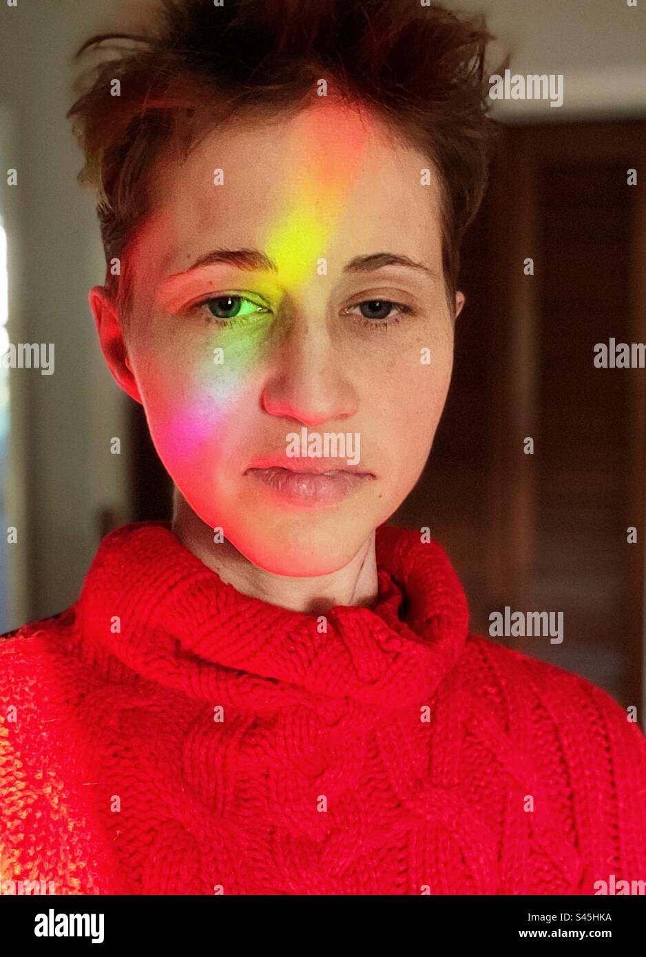 Maglione rosso con luce arcobaleno sul viso Foto Stock