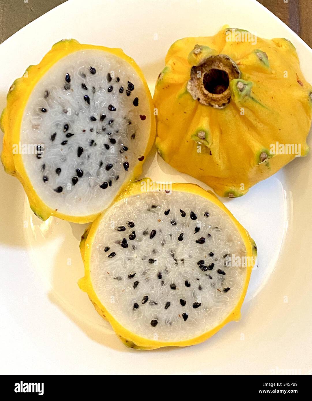 Tagliare la frutta del drago giallo – Pitahaya – su un piatto. Foto Stock