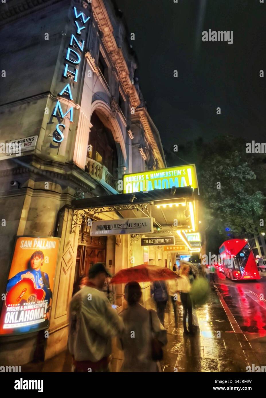 Il Wyndham Theatre è stato classificato di grado II* dall'English Heritage nel settembre 1960 visto di notte con una nuova produzione di Oklahoma - gli ombrelli sono sulla strada piovosa nel West End di Londra Foto Stock