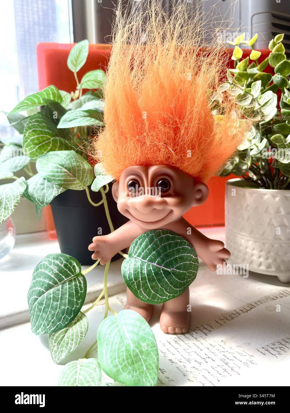 bambola troll dai capelli arancioni tra le piante in vaso Foto Stock