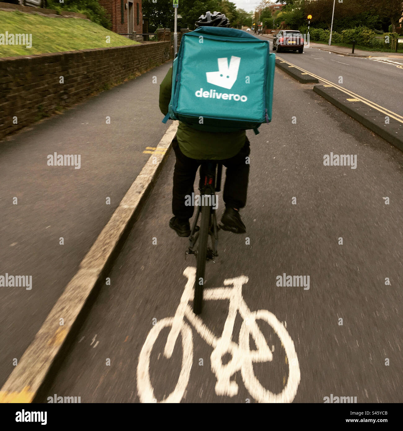 Deliveroo Cyclist fa un giro in bicicletta lungo la pista ciclabile. Foto Stock