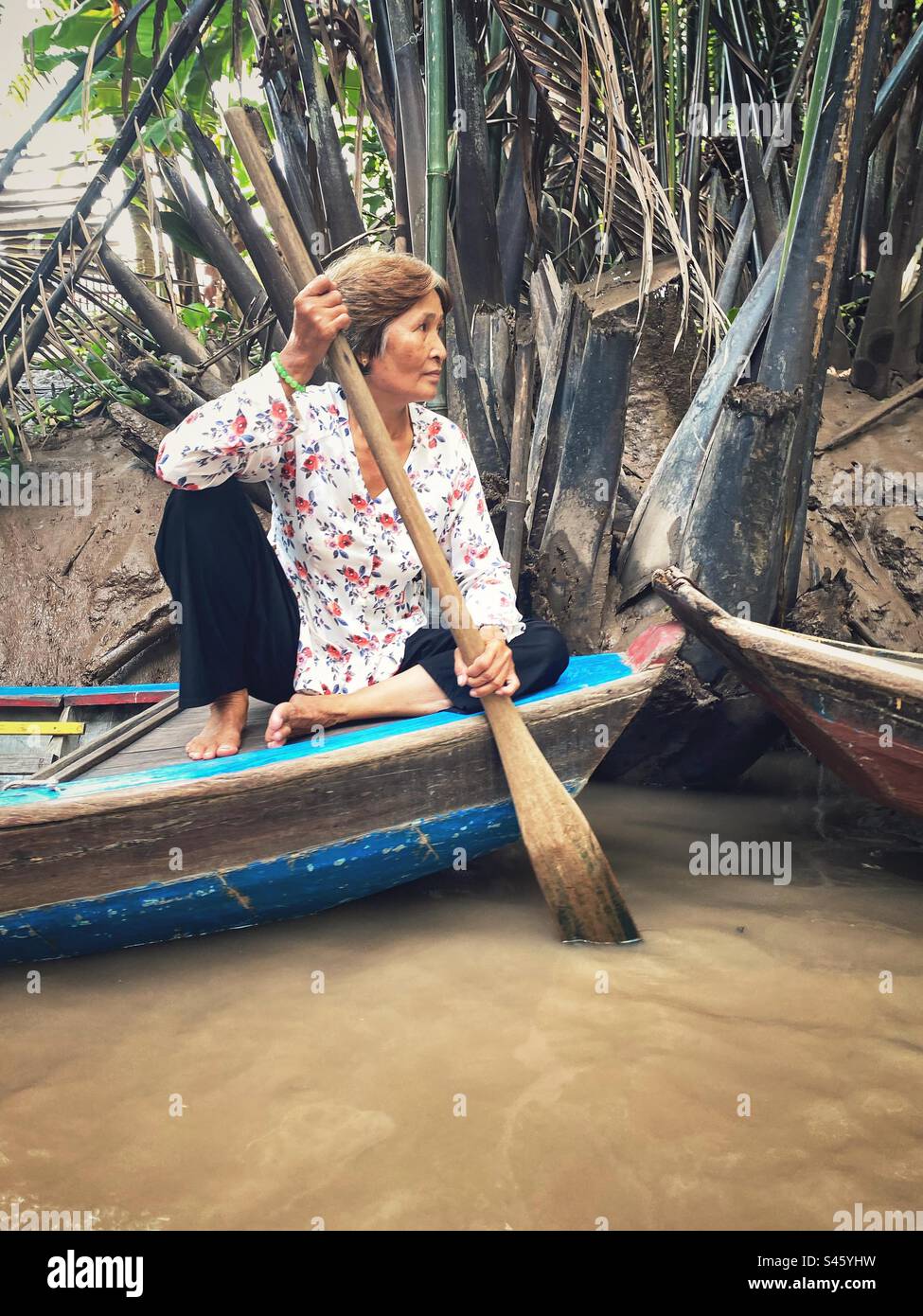 Tour del delta del Mekong sull'isola di Thoi Son, Vietnam. Una donna del posto e la sua barca di legno. Foto Stock