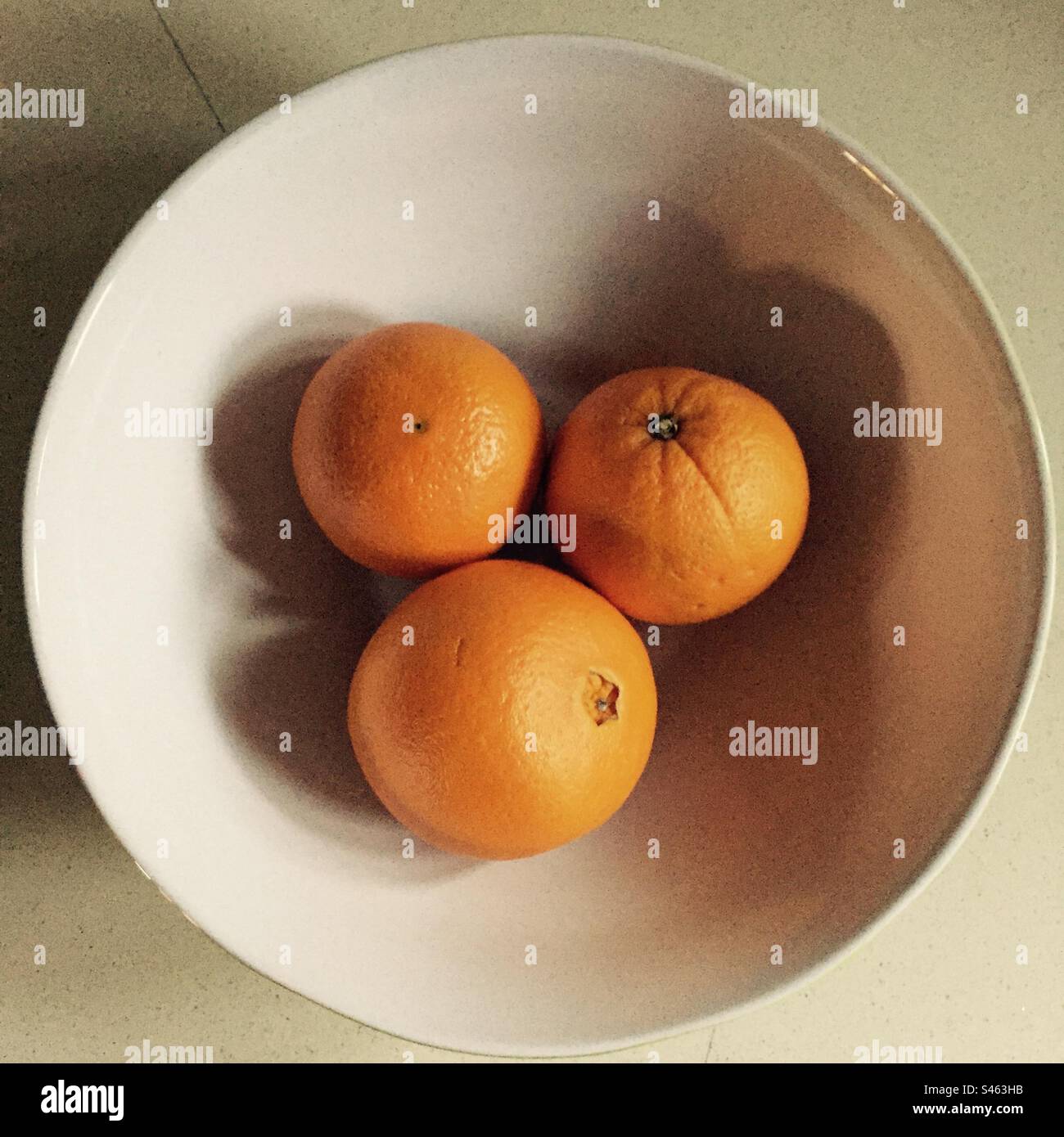 Tre arance in una ciotola bianca Foto Stock