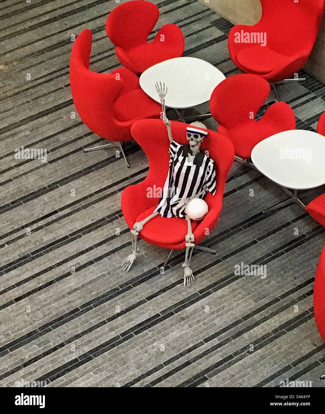 Uno scheletro in maglia a righe con pallavolo - Immagine stock catturata con smartphone