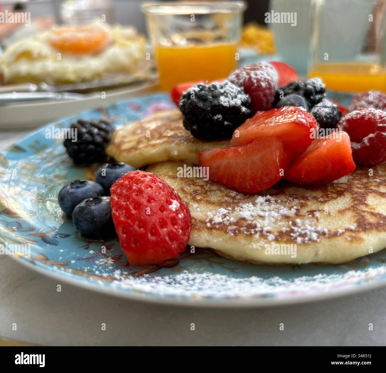 Una sana colazione con pancake con sciroppo d'acero e frutta rossa, fragole,  lamponi, more e mirtilli, come bevanda un buon succo d'arancia Foto stock -  Alamy