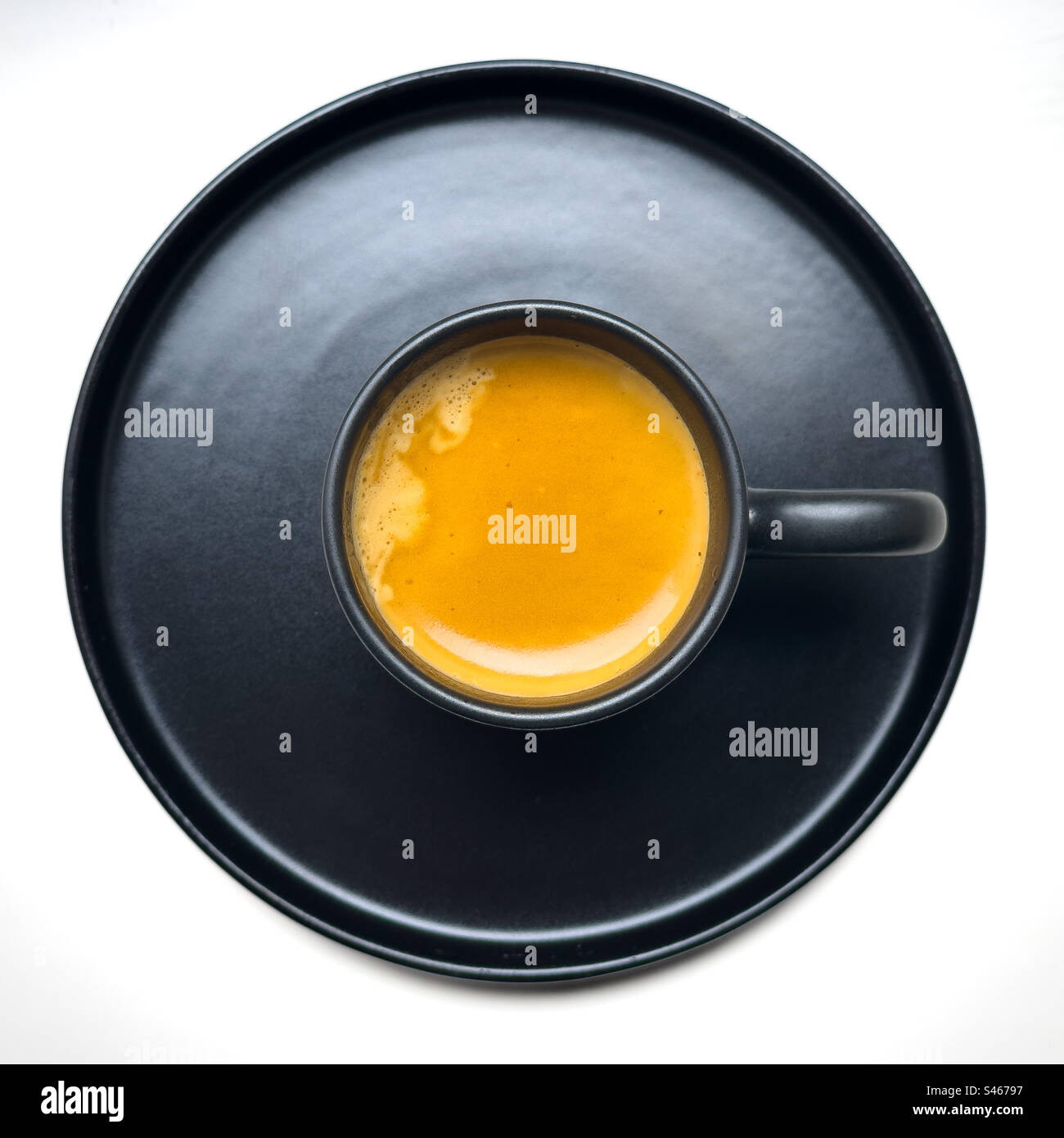 Crema espresso in tazza nera e piattino - Immagine stock catturata con smartphone