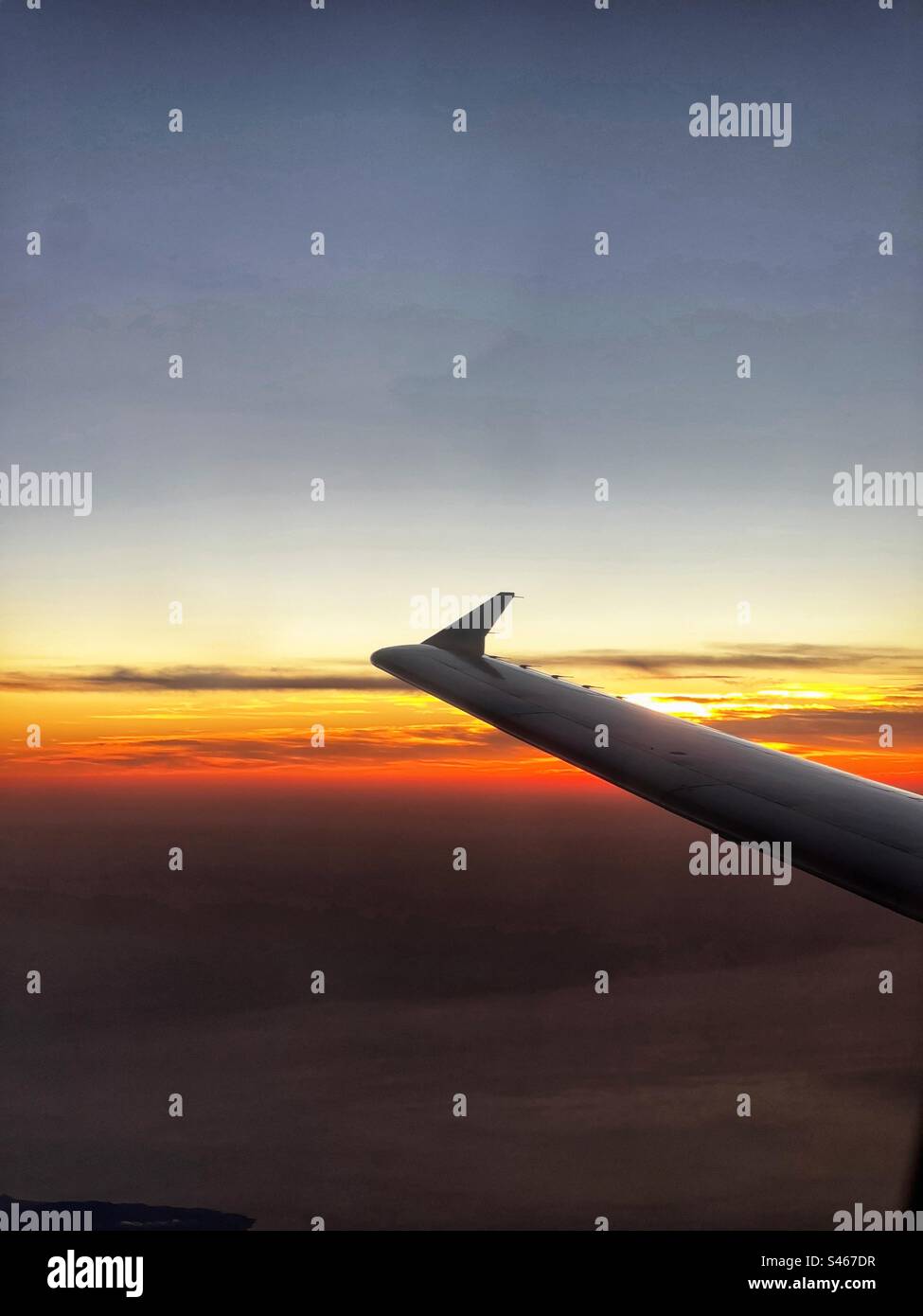 Silhouette dell'ala di un jet da vacanza in volo contro un cielo colorato al tramonto. Concetto di viaggio. - Immagine stock catturata con smartphone