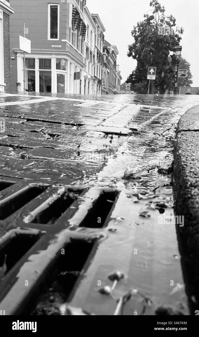 L'acqua piovana scorre dalla strada al pozzo Foto Stock