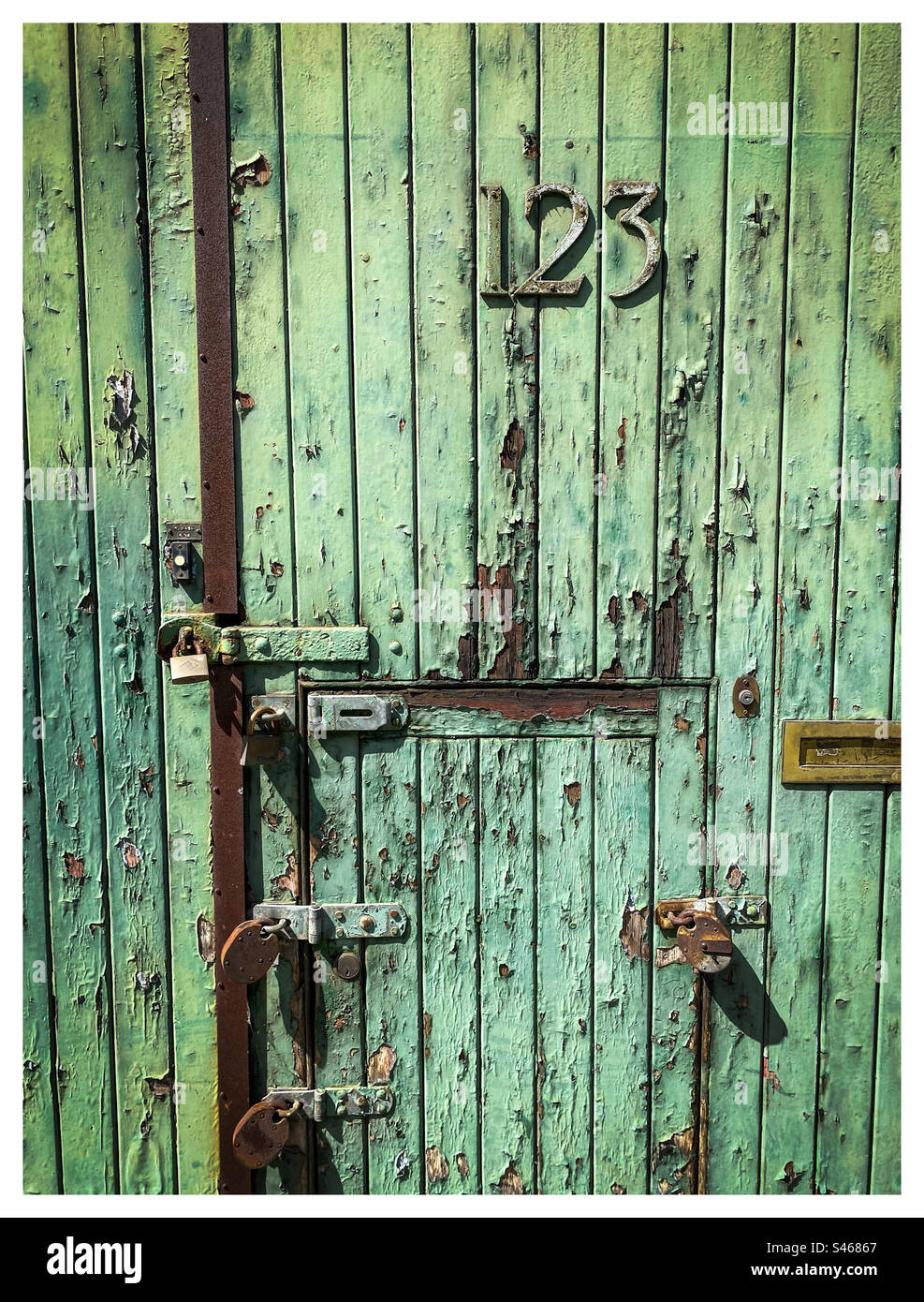 La vernice si stacca da una vecchia porta verde numero 123 Foto Stock